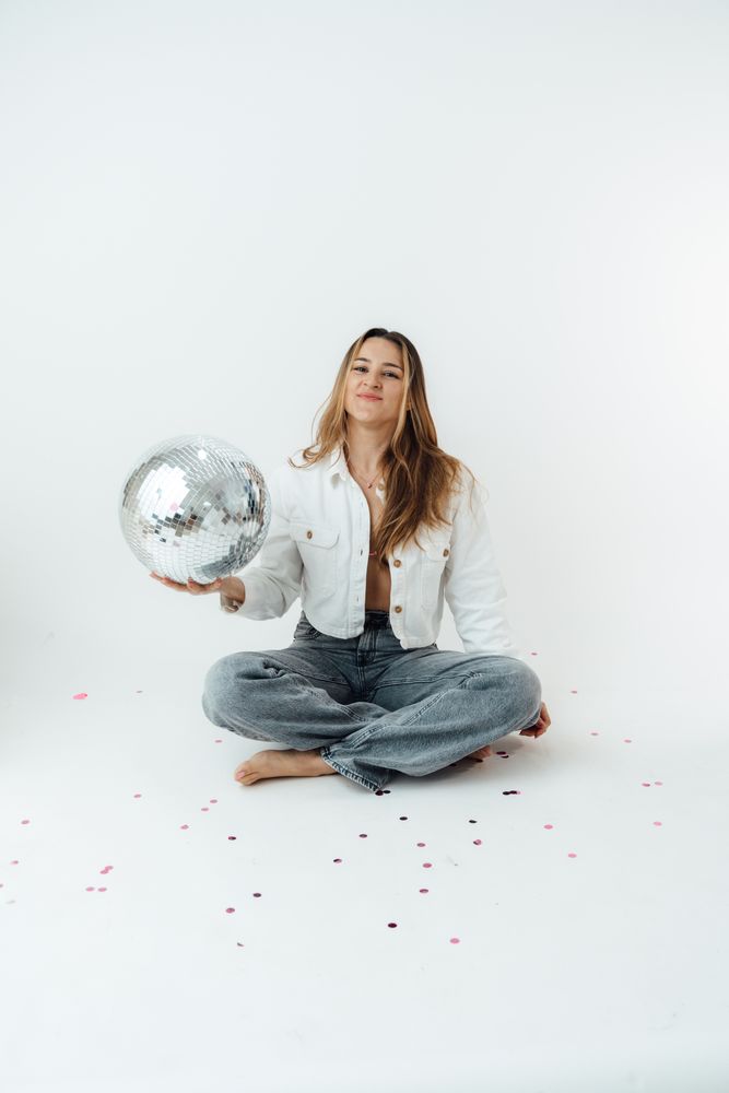 La fotógrafa sentada en el piso del estudio con una bola de disco