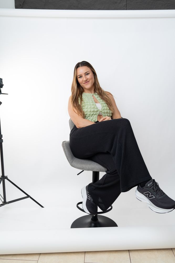 La fotógrafa sentada en un banco en su estudio, junto a una luz