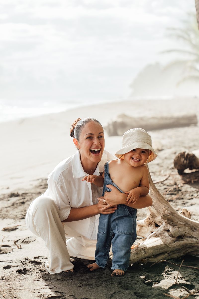 Mamá riendo con su bebé en la arena